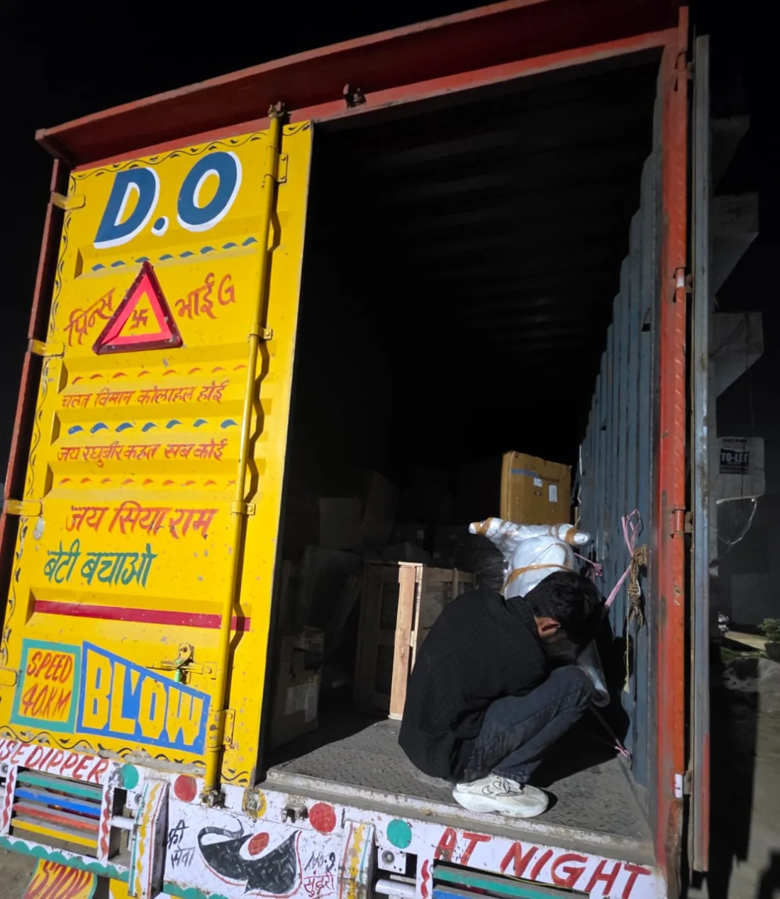 Household truck being loaded at night for an NCR hop — wrapped furniture lashed on an HR-registered goods body